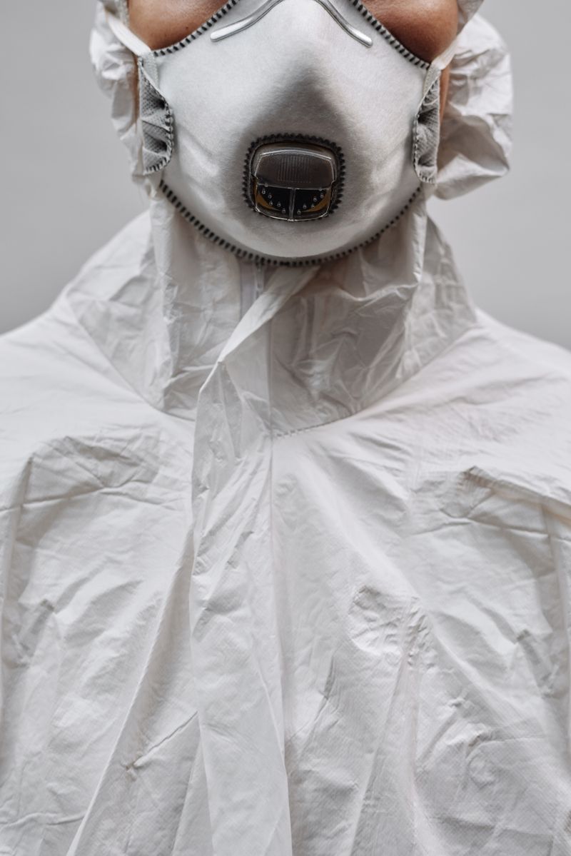 Worker in full chemical PPE including respirator mask, splash goggles, and protective suit for acid spill response