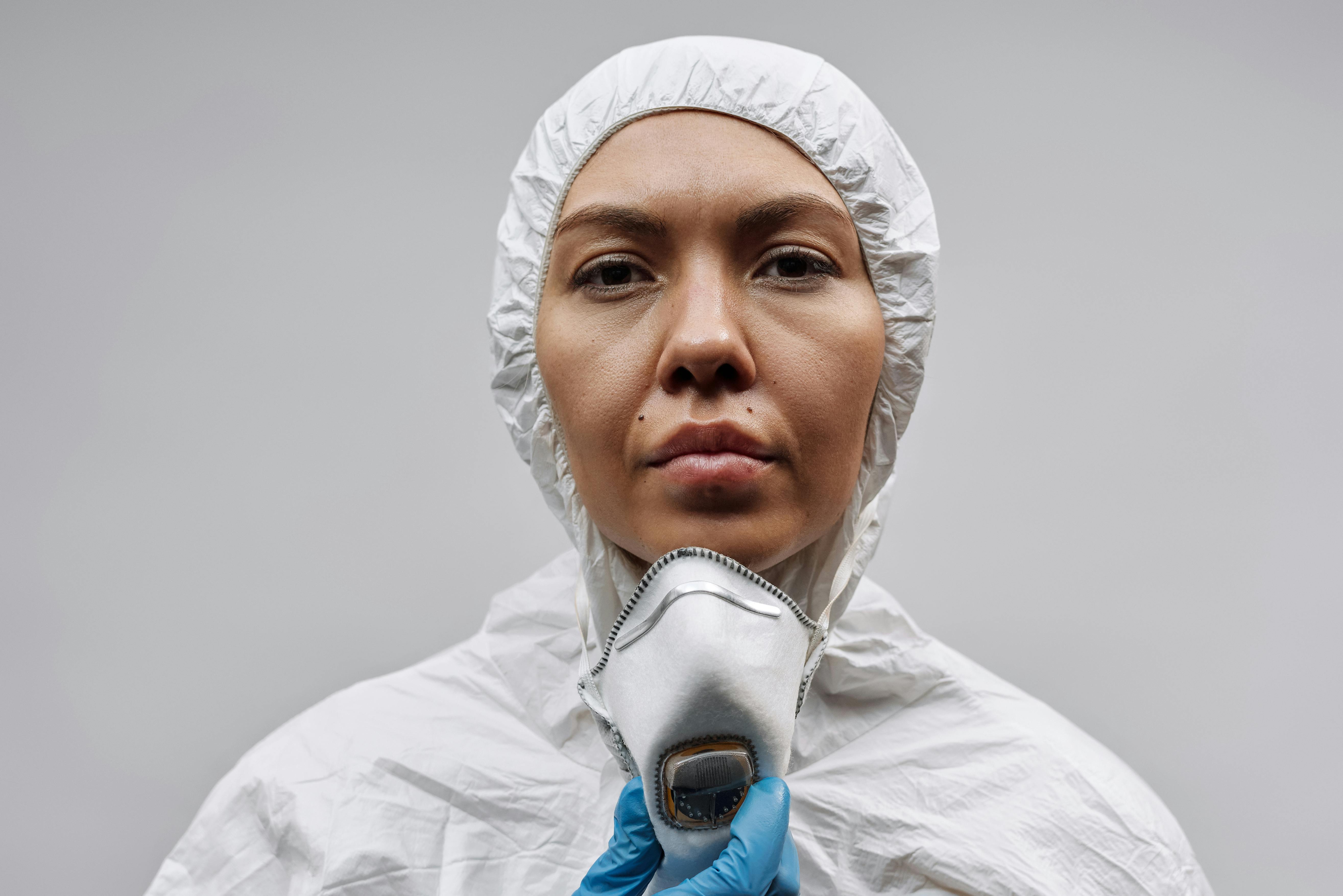 白色背景上，一名穿着个人防护装备、戴着口罩和手套的妇女的特写镜头