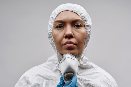 白色背景上，一名穿着个人防护装备、戴着口罩和手套的妇女的特写镜头