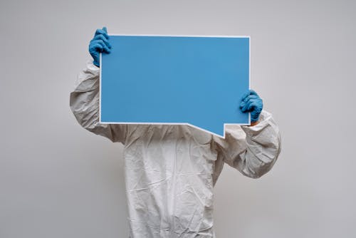 Person in White Coveralls Holding Blue and White Board