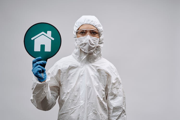 Person In White Protective Clothing Holding A Signage