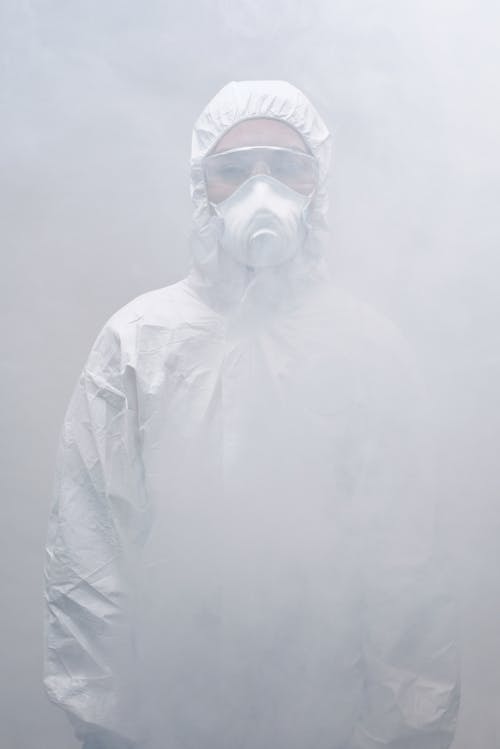 A Person Wearing Personal Protective Equipment Standing in Smoke