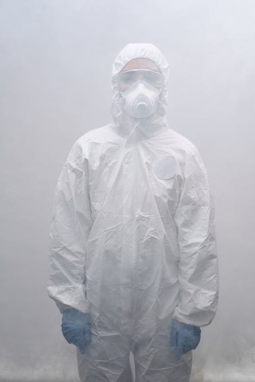 Person in Personal Protective Equipment Standing in a Smokey Room