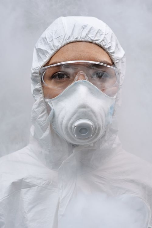 Free Close-up image of a person wearing protective gear, goggles, and a mask, surrounded by mist. Stock Photo