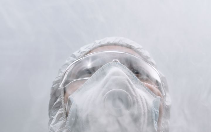 A person in protective gear and mask, surrounded by smoke or mist, illustrates safety measures.