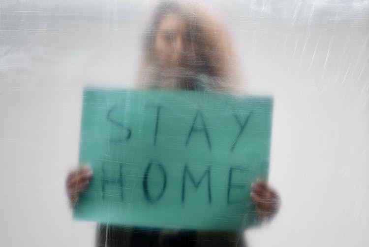 Woman Holding Green Signage Behind Plastic Sheet