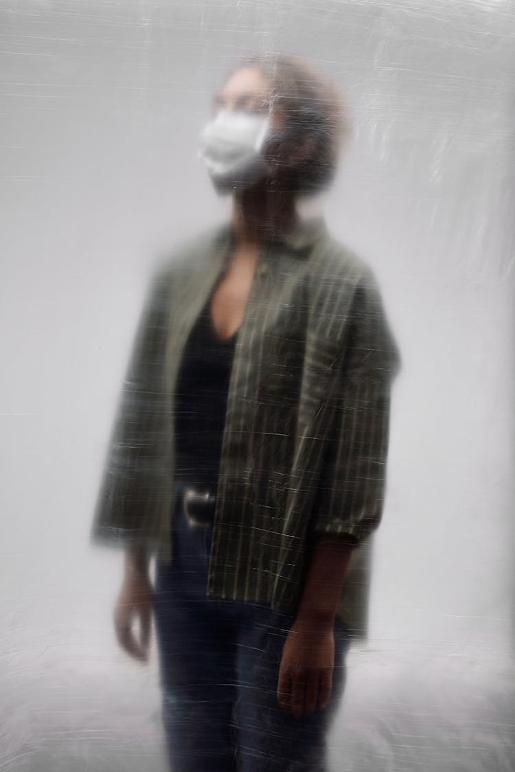 Woman In Striped Green Top And Face Mask Standing Behind Blurred Plastic Sheet