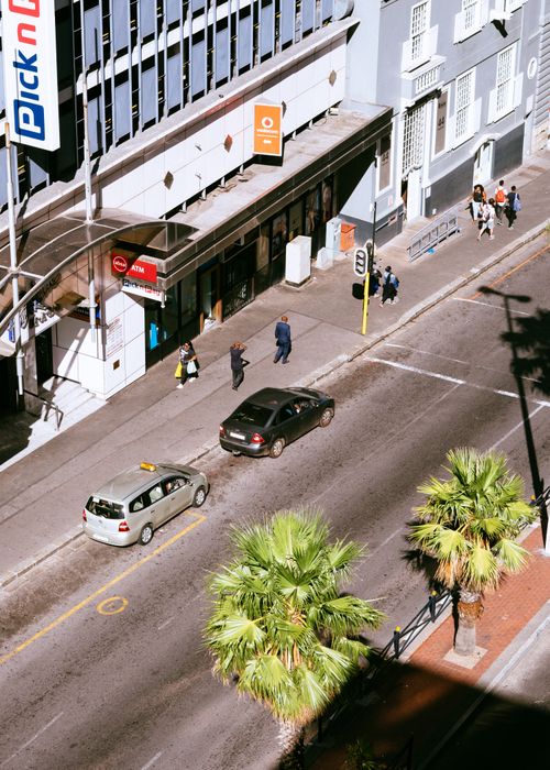 Free From above of city street with cars parked on roadside and people walking on sidewalk Stock Photo