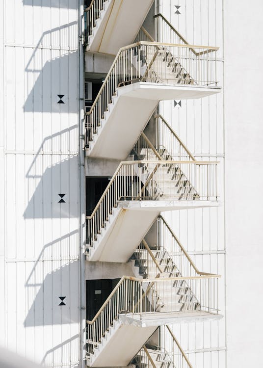 High stairway of contemporary stairway with metal railing of white wall of building in sunlight