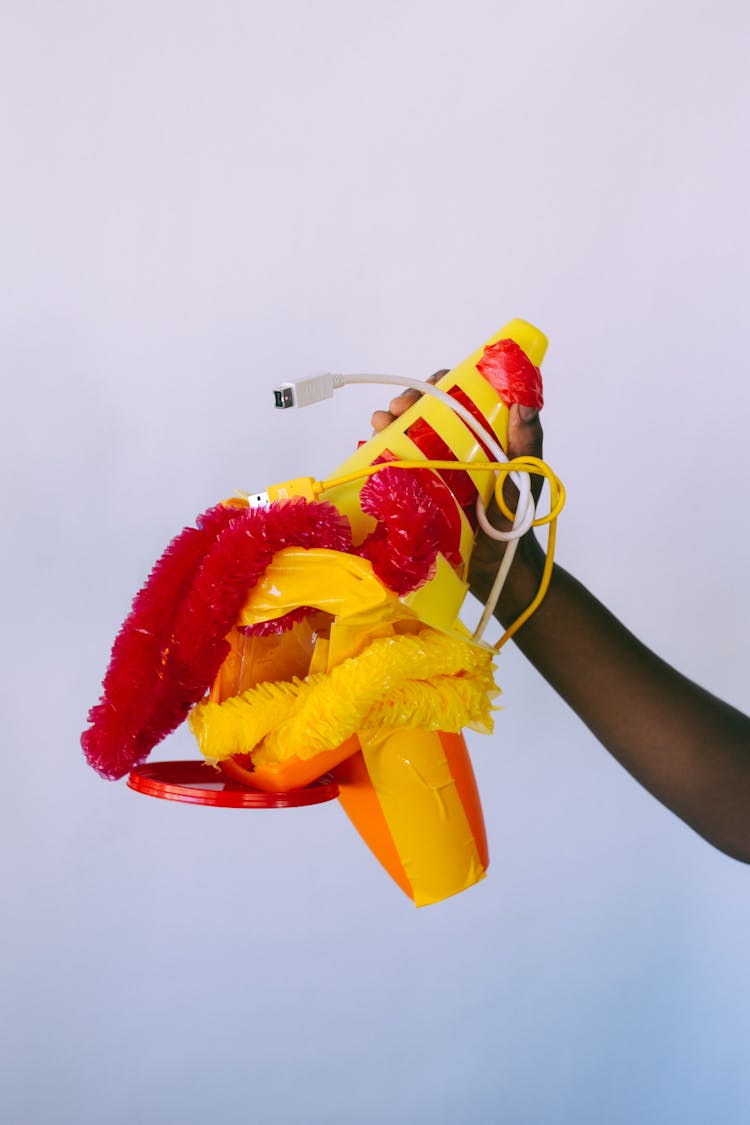 Crop Black Person Showing Unsuitable Plastic Items On Gray Background