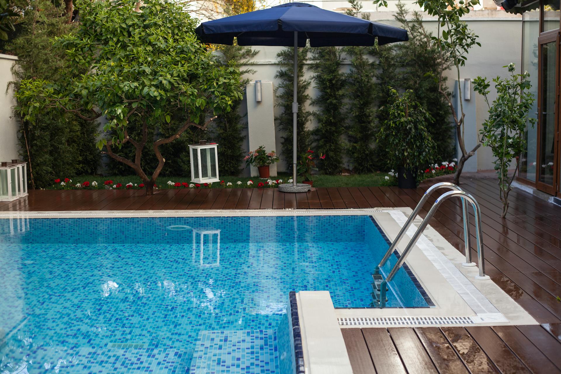 Serene backyard featuring a swimming pool, lush garden, and wooden deck in Antalya, Turkey.