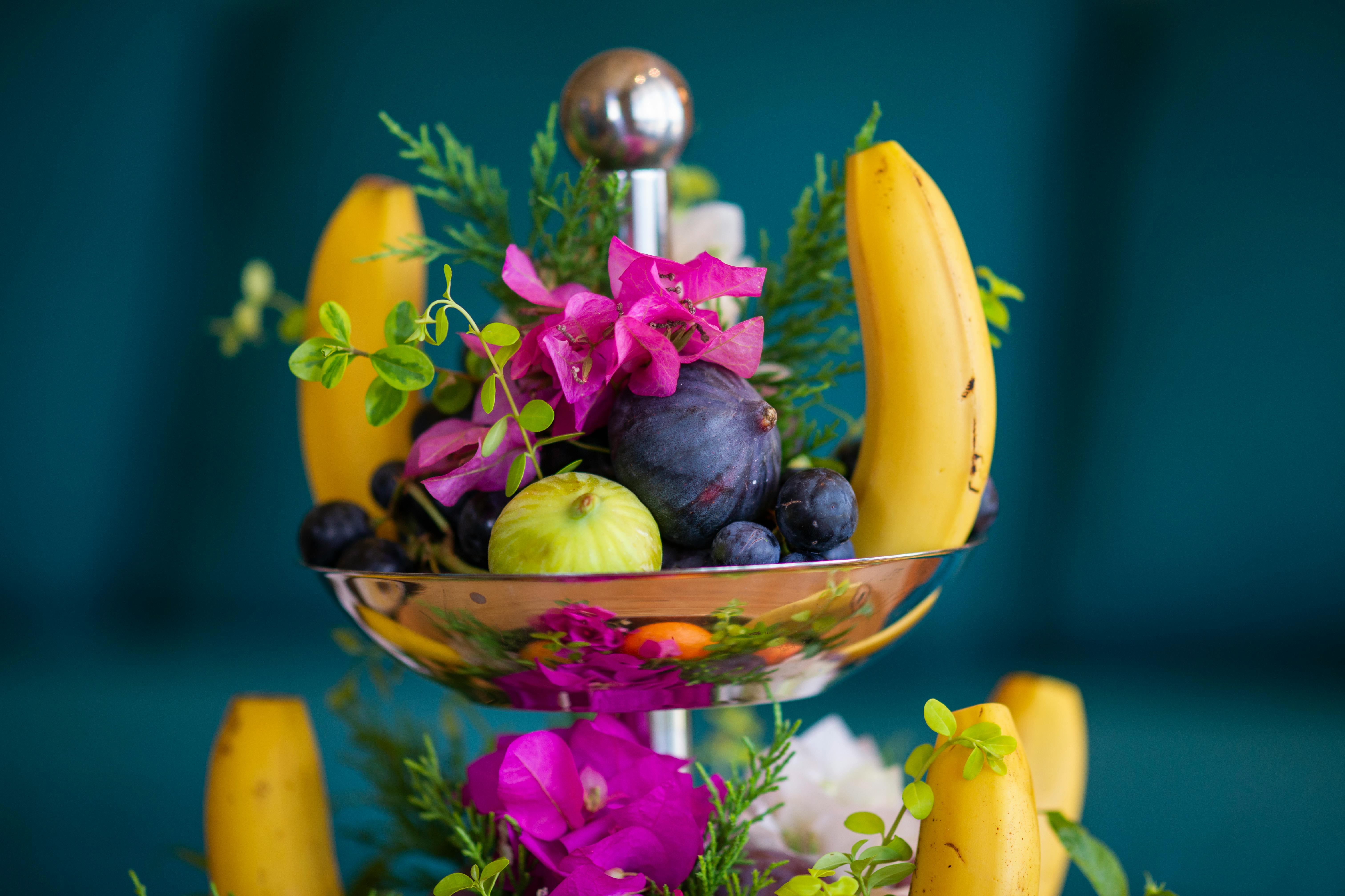 A bowl of fruit with florals.