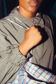 Confident woman holding a plaid shopping bag, wearing a stylish jacket. Urban fashion vibe.