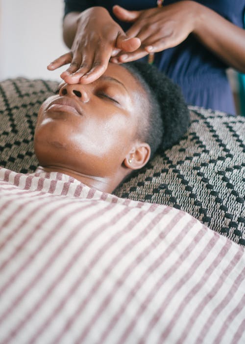 Happy ethnic woman enjoying massage in salon