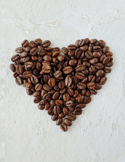 Free Heart-shaped arrangement of coffee beans on a textured surface, perfect for coffee lovers and cafes. Stock Photo
