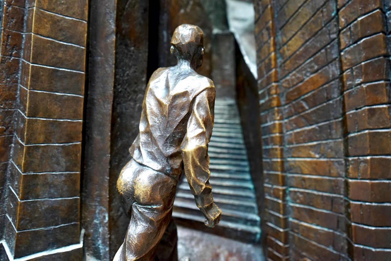 close up of a metal sculpture depicting a man walking through narrow u