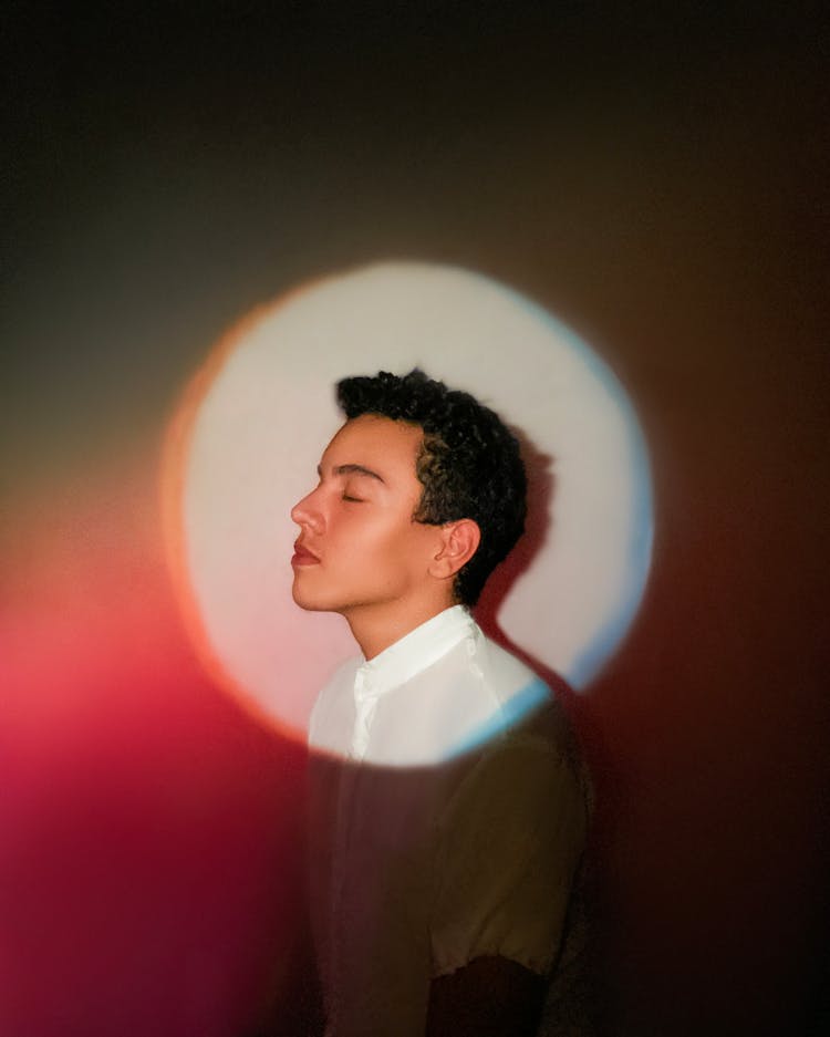 Young Man Standing Near Wall With Spotlight