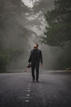 摄影师走过一条薄雾缭绕的森林道路，展现出孤独与探索的氛围