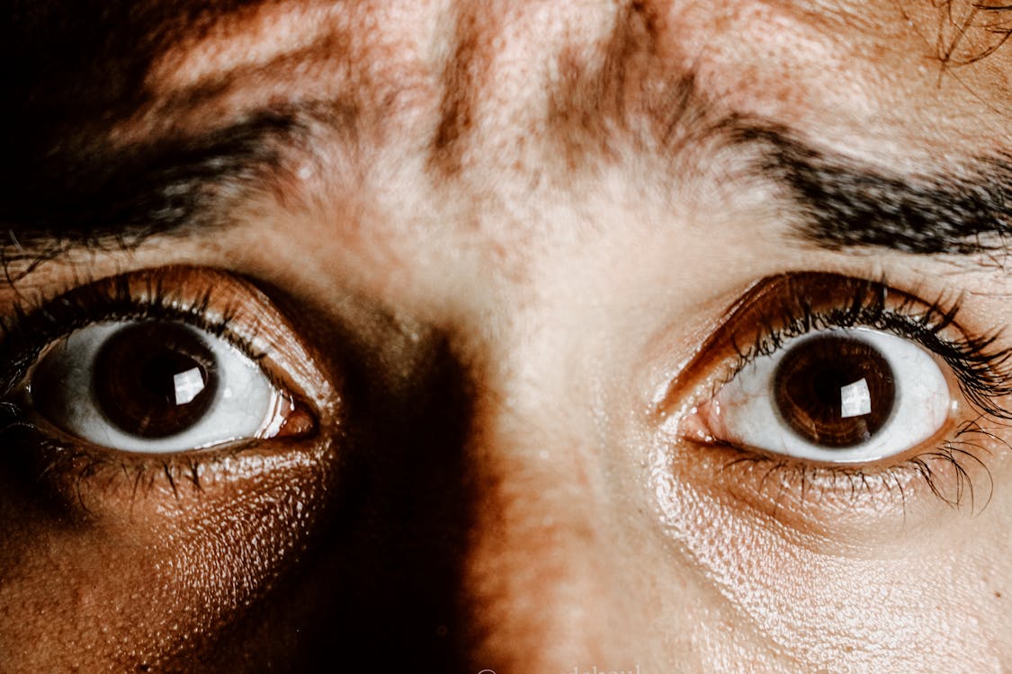 Crop face of person with brown eyes with fear on face looking at camera