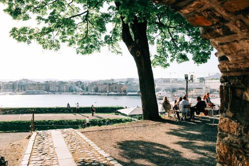 Free People sitting at tables in outdoor cafe in waterfront and enjoying calm river and sunny day Stock Photo