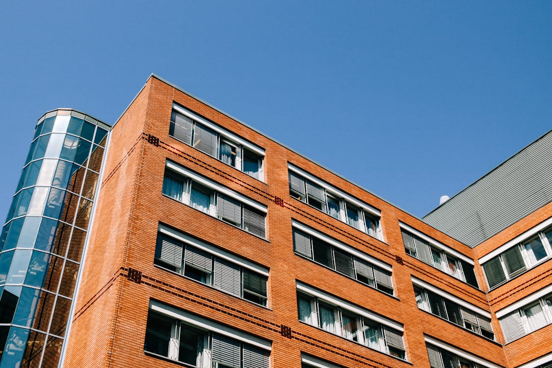 Free From Below Of Contemporary High Apartment Building Located In Residential District Against Blue Sky Stock Photo