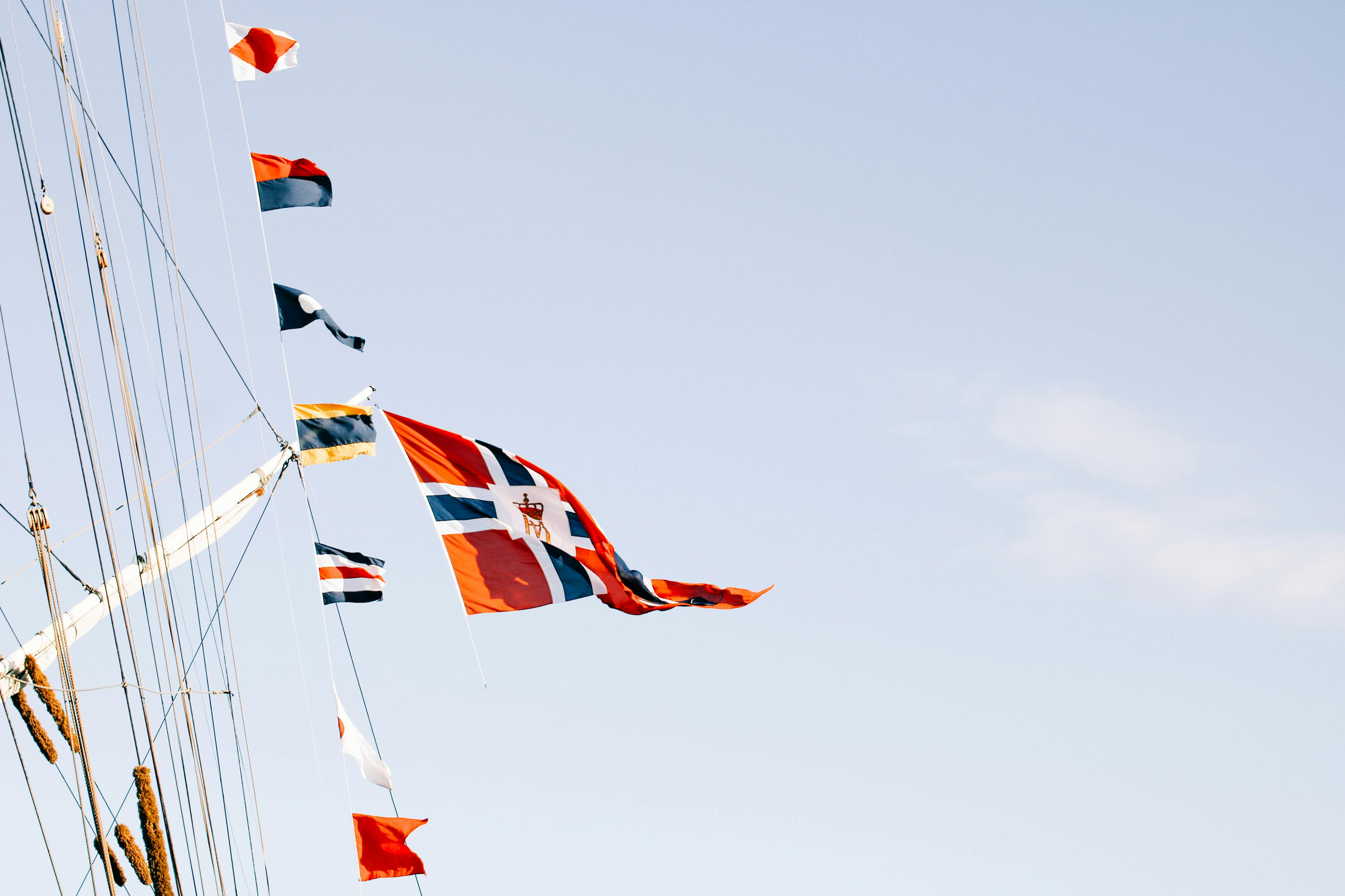 various flags waving on rope against blue sky