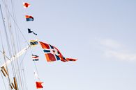 Various flags waving on rope against blue sky