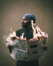 Thoughtful Arabian male holding newspaper with bright flashes of fire and looking away