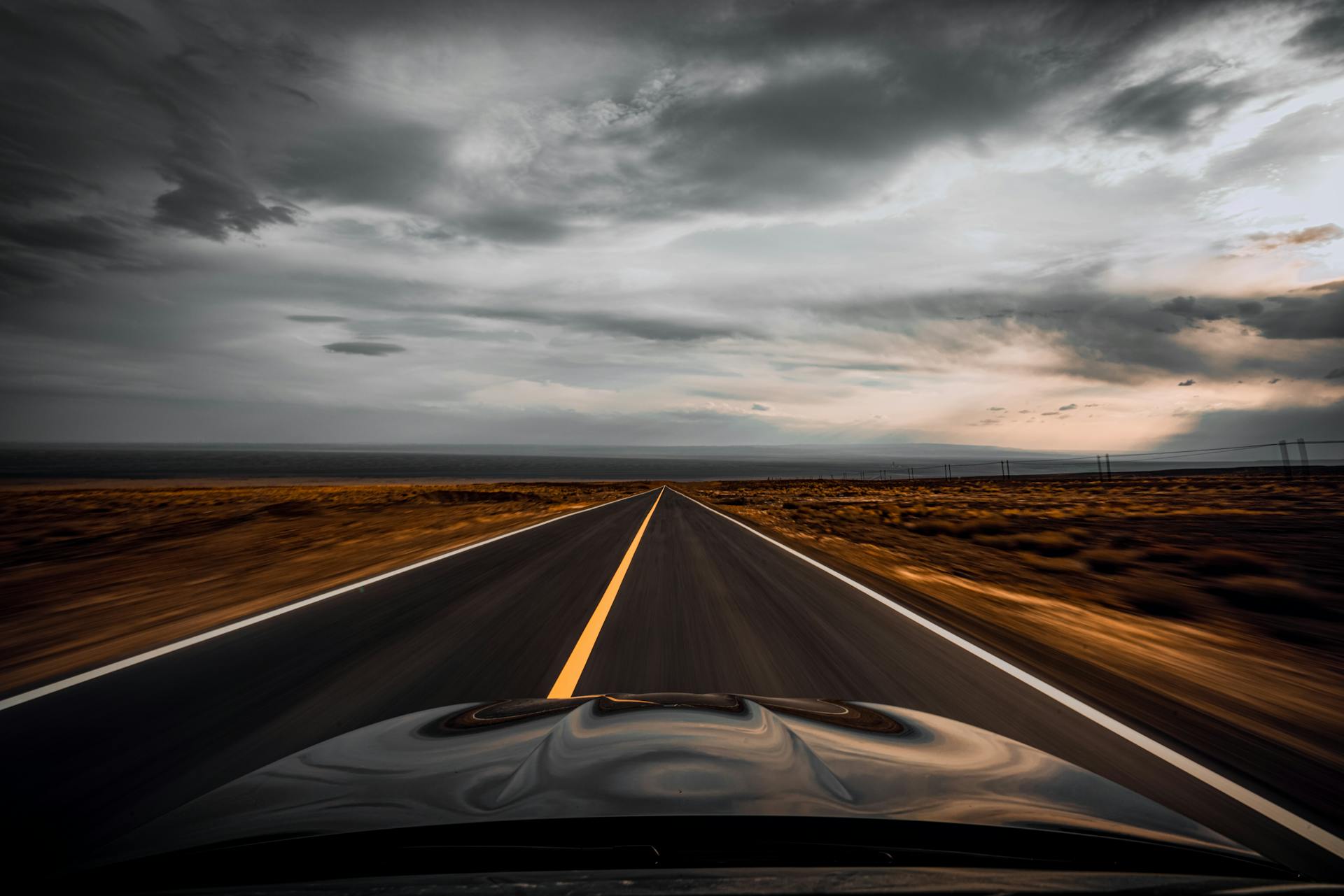 Auto driving through dry desert valley on long straight roadway in overcast weather