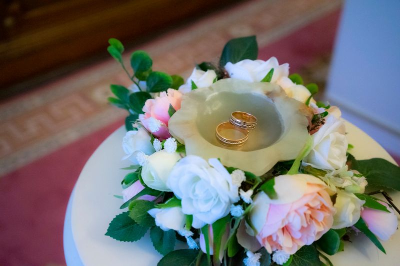 Two gold rings on a ceramic plate with a pastel bouquet