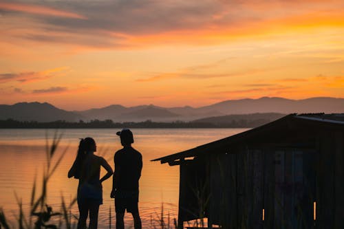 Silhouette of Two People standing on Lakeside 