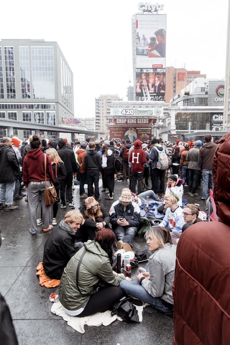 Group Of People Sitting On Pavement In City