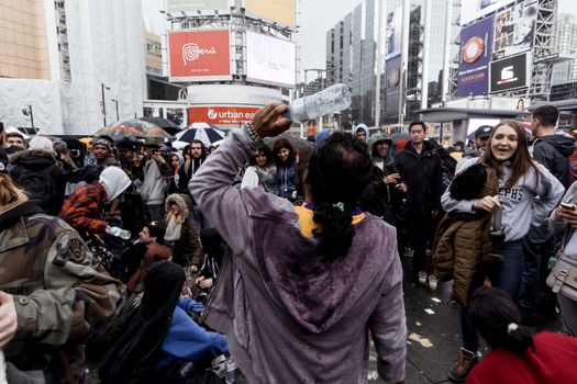 节日期间，一群穿着保暖衣服的人站在城市现代建筑间拥挤的街道上