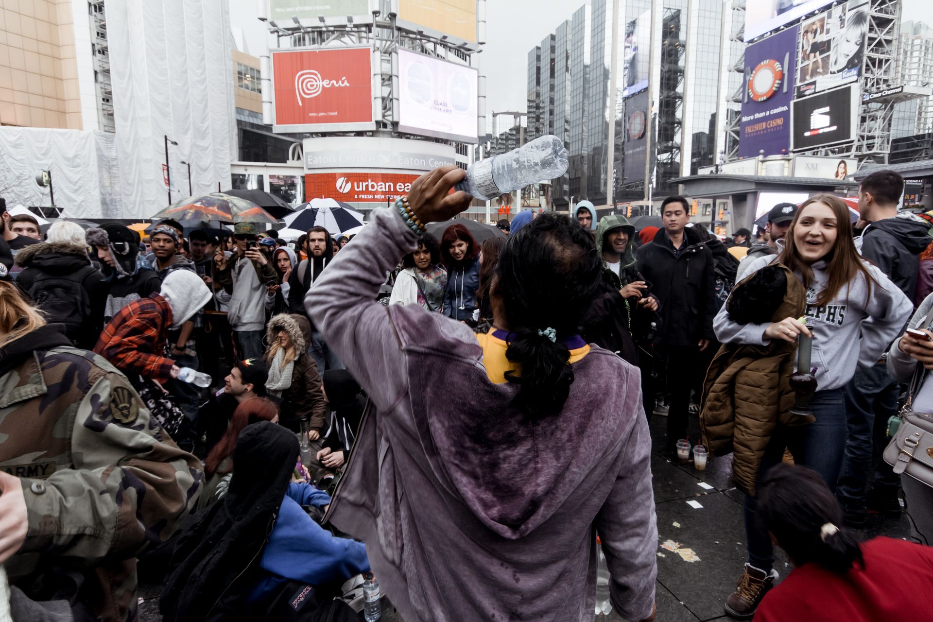 Group of people in warm clothes standing on crowded street amidst contemporary buildings in city during mass festival in daytime
