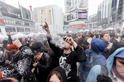 Group of people gathering on street amidst modern buildings and smoking cigarettes while standing in city in overcast weather outside