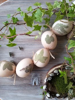 质朴的木桌上，放着一枚手工制作的装饰性复活节彩蛋，上面有叶子图案，周围环绕着常春藤