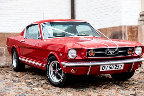 Free Vintage red car parked on pavement near building with white brick wall in city street during daytime in summer day Stock Photo