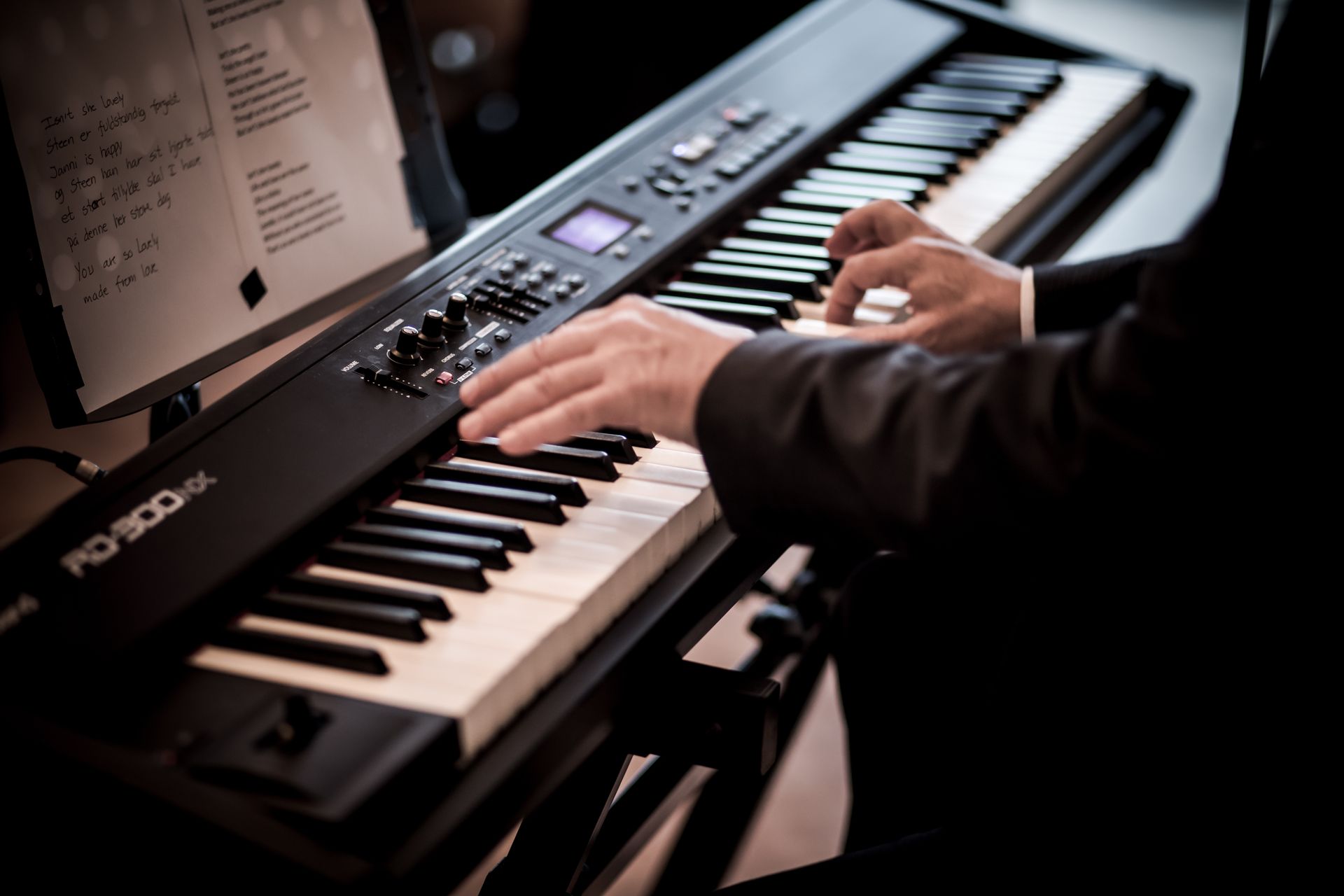 A professional musician elegantly playing a digital piano in a studio environment.