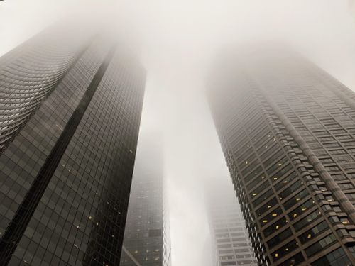 Free From below of contemporary tall business centers with glass reflecting windows located against misty sky on street in downtown outside Stock Photo