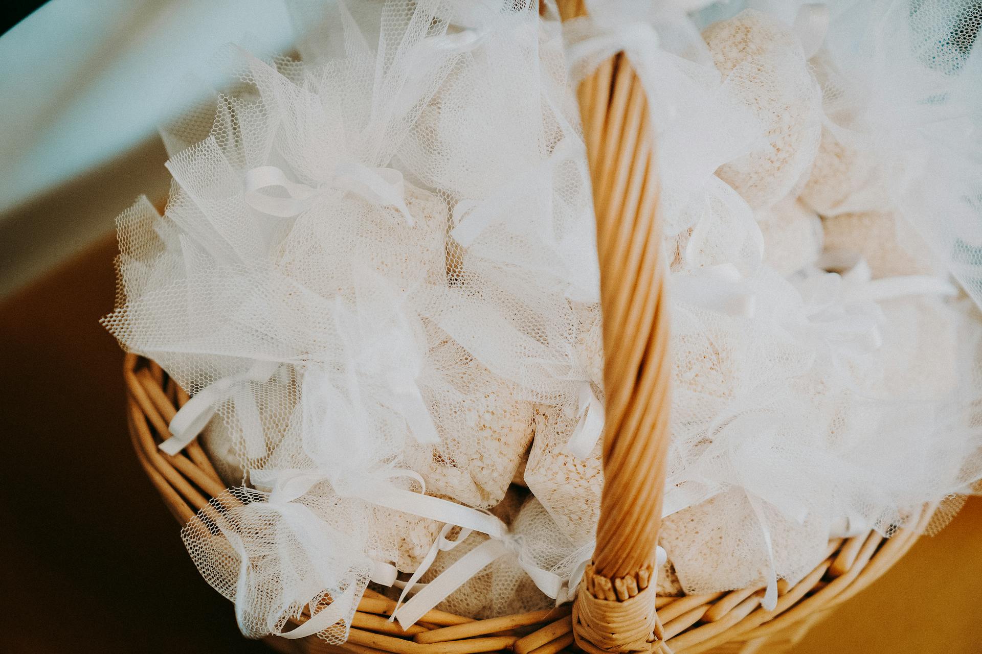 Wicker basket filled with delicate white organza gift bags, perfect for weddings or celebrations.