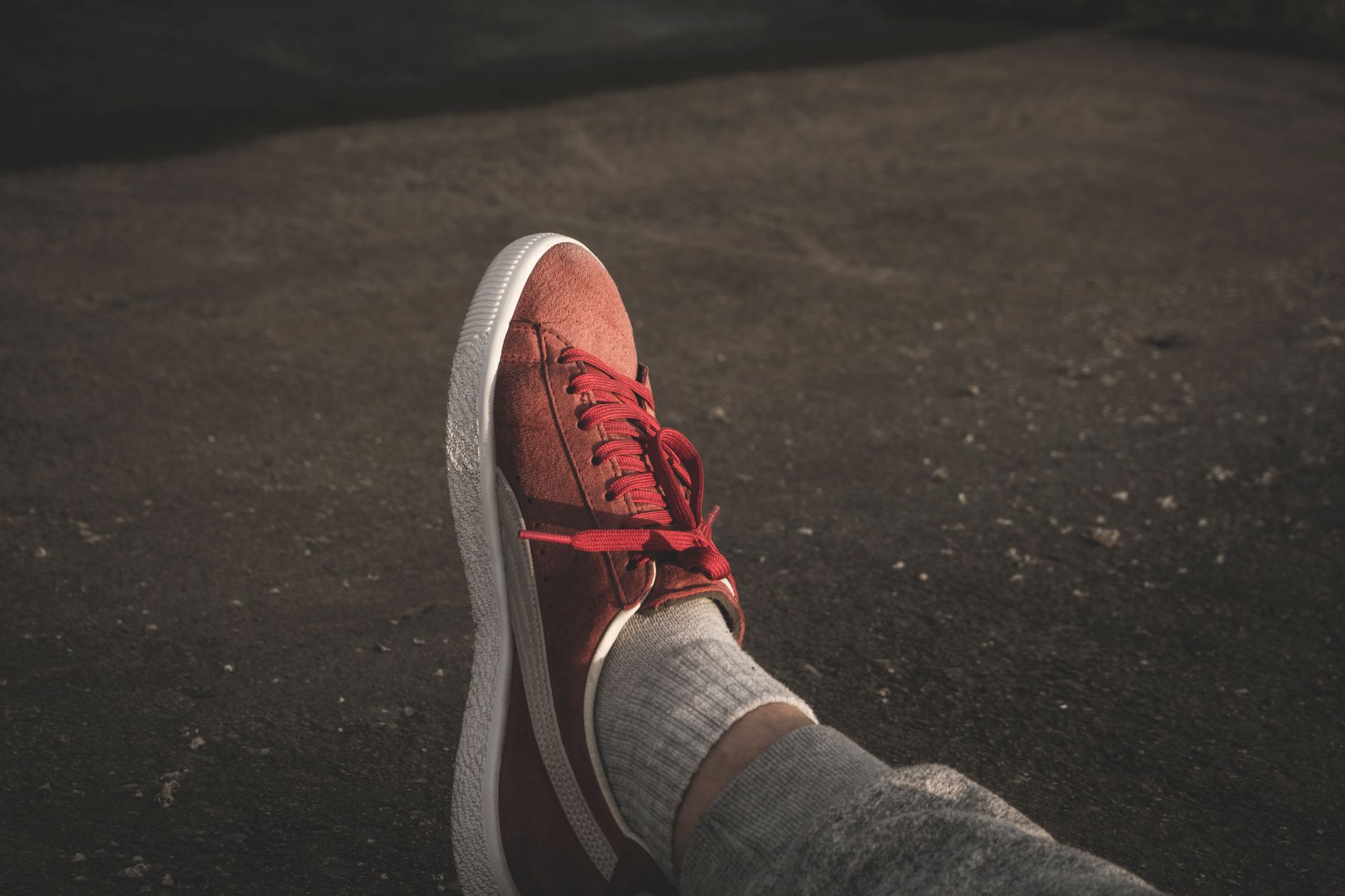 Close-up of red sneakers worn outdoors on pavement. Urban lifestyle vibe.