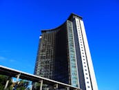 从低角度观看，一座引人注目的现代摩天大楼的玻璃板映衬着充满活力的蓝天