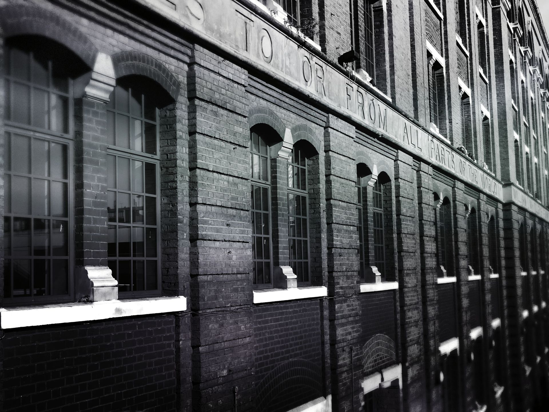 A black and white photo of a historic brick building featuring tall arched windows and architectural details.