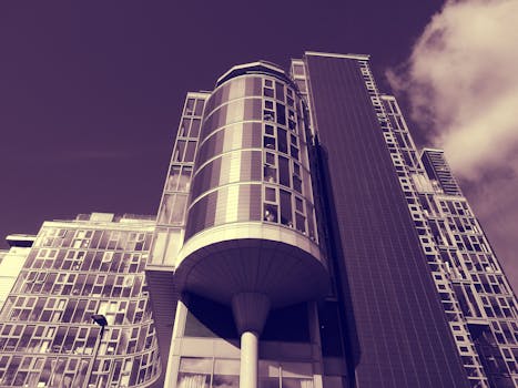 低角度拍摄的多云天幕下，现代摩天大楼的未来主义玻璃立面