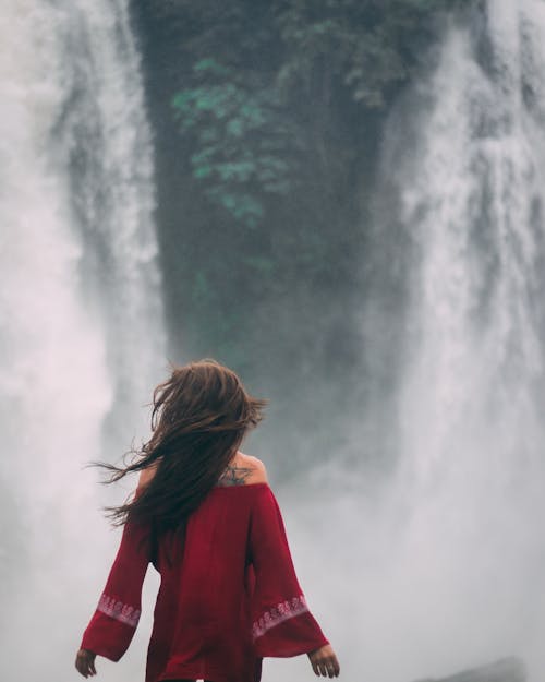 Woman in Red Dress standing near Waterfalls 