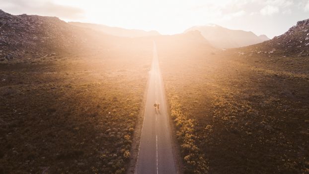 Stunning aerial view of a solitary road in Cape Town's rural landscape at dawn, bathed in warm sunlight.