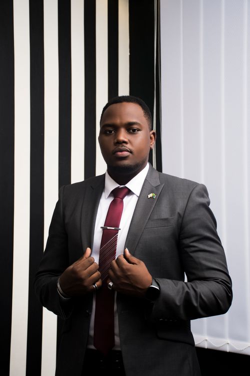 Free Portrait of a confident businessman in formal attire against a striped background. Stock Photo