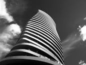 现代摩天大楼的弧形设计和玻璃元素，映衬着多云的天空