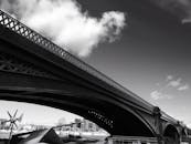 这张黑白照片从低角度拍摄，捕捉了一座大型城市桥梁的引人注目建筑细节