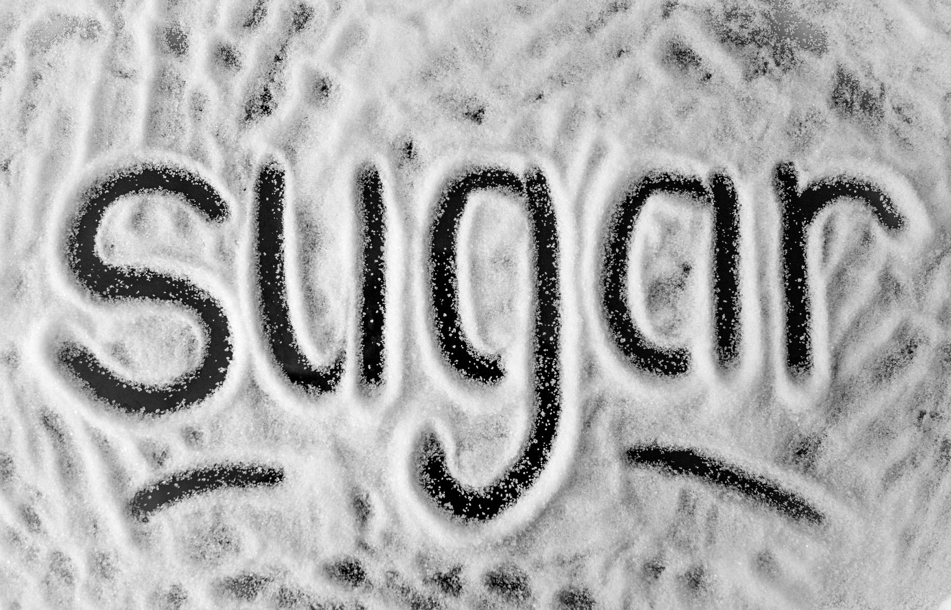 Hand measuring superfine sugar from a jar for a baking project